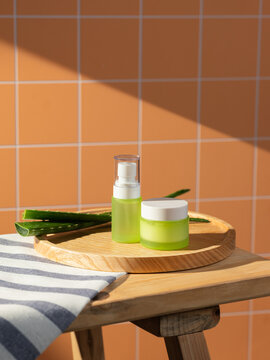 Natural skincare products with fresh aloe vera leaves on a wooden tray