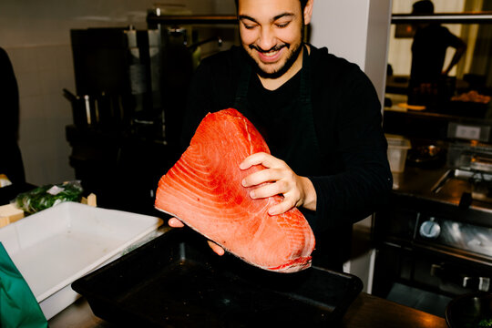 Medium shot of a chef weighing fresh fish on a kitchen scale