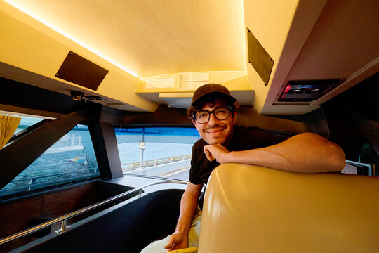 Man relaxing inside VIP bus with coastal view through window