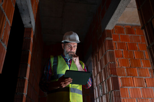 Man in safety gear looks at a tablet on site