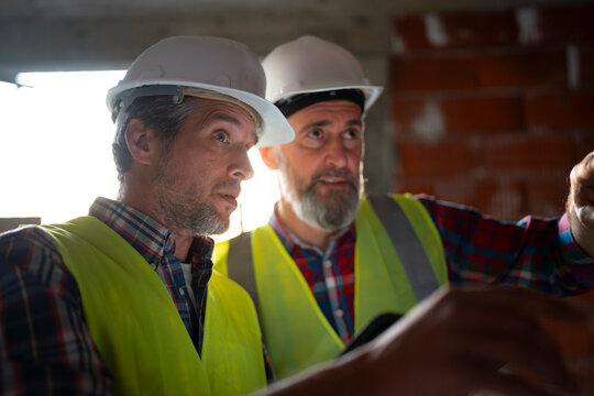 Two workers discussing plans on construction site