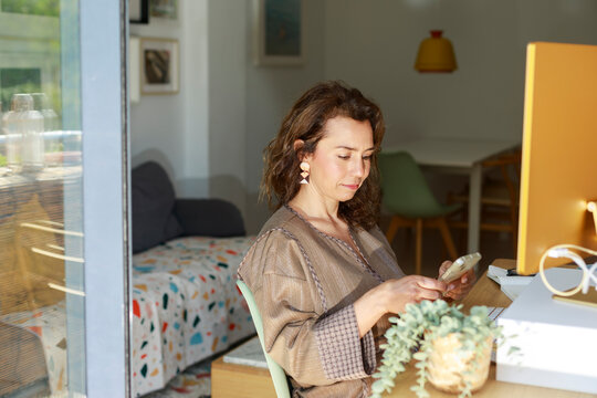 Woman Working on Phone in a Modern Workspace During the Day