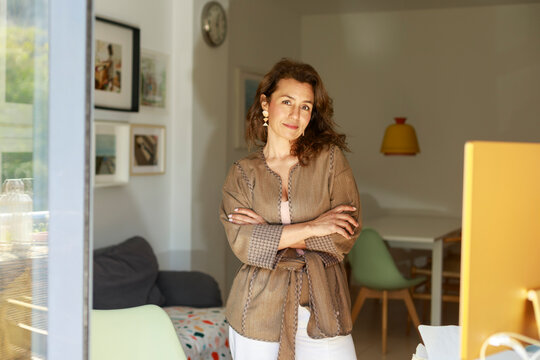 Woman Stands in Room With Natural Light While Crossing Arms
