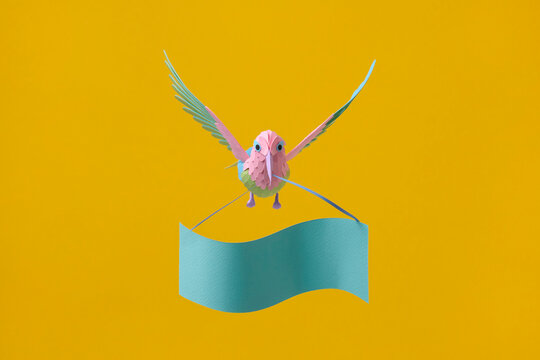 Paper hummingbird above banner on yellow background