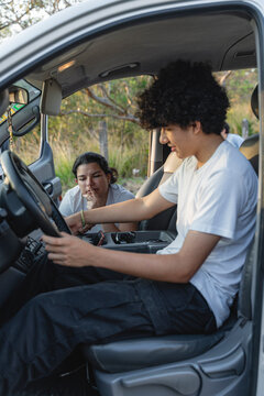 Teenage son learning to drive car with mother's guidance