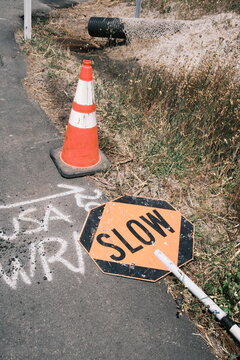 Fallen Slow Sign and Traffic Cone on Road Construction Site