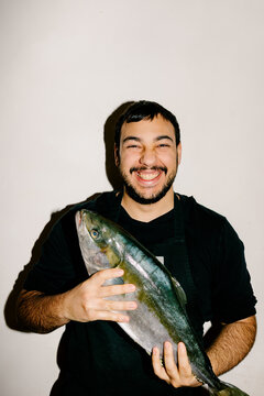 Portrait of a chef grinning while holding a freshly caught fish