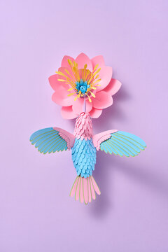 Paper hummingbird with flower on purple backdrop
