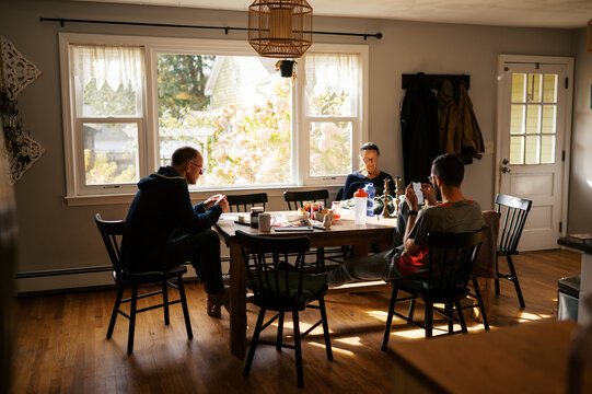 family relaxing at breakfast table indoors using cell phone