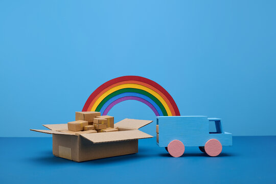Toy delivery truck and open box filled with packages against a blue