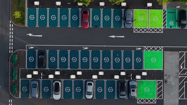 Aerial view of electric vehicle charging station at Rugby Services with cars parked in green and blue marked bays in Rugby, England, United Kingdom.