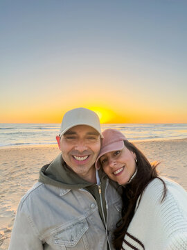 Couple hugging taking selfie at beach sunset
