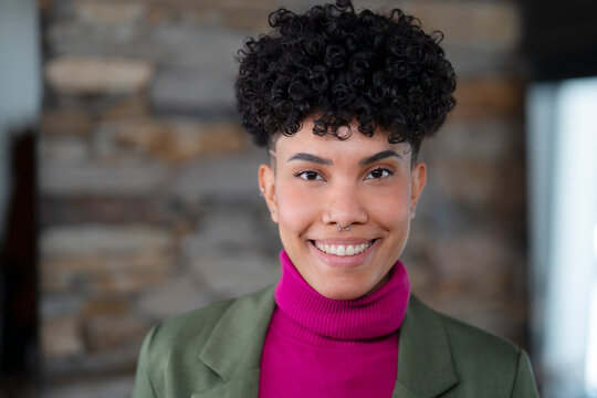 Person with curly hair smiles in a colorful outfit