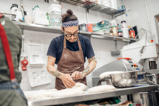 Baker man shaping dough in artisanal kitchen