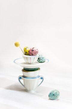 Colorful eggs stacked on teacups in a simple setup 