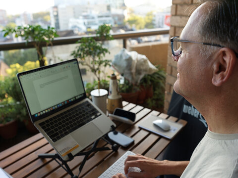 Man Working on Laptop at Balcony in the Morning Sunlight