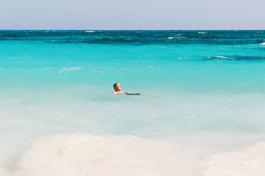 Man floats while swimming in turquoise water of the Bahamas