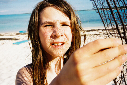 Child looks at seaweed found on the beach in the Bahamas