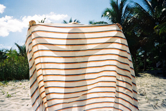 Shadow silhouette of girl behind towel on tropical beach