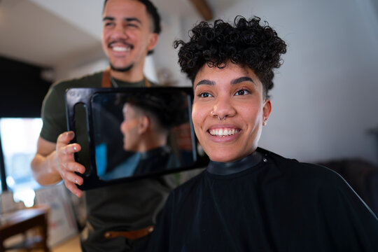 A hairstylist shows a tablet to a smiling client