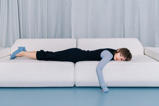 Minimal fashion portrait woman lying on sofa looking at camera