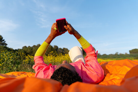 Person Using a Smartphone While Lying in a Field 
