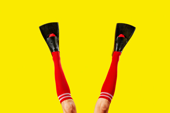 the legs of a man extend in red socks with diving fins
