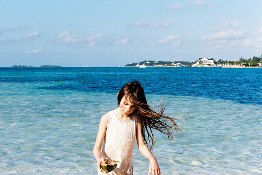 Girl on Bahamas beach playing with coconut shell