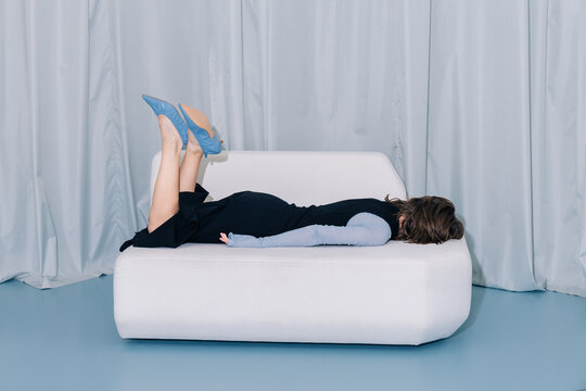  Playful fashion pose woman lying face down on minimal sofa