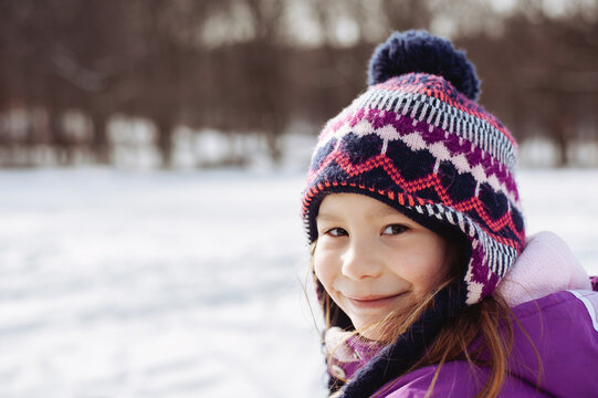 Winter portrait of a smiling young girl out in the snow.