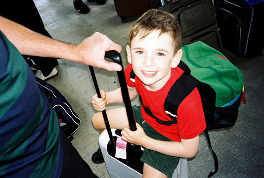Portrait of child riding on suitcase while traveling with family