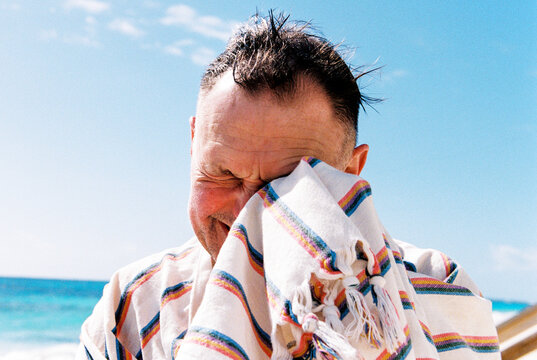 Awkward portrait of man wiping water from his eyes with towel