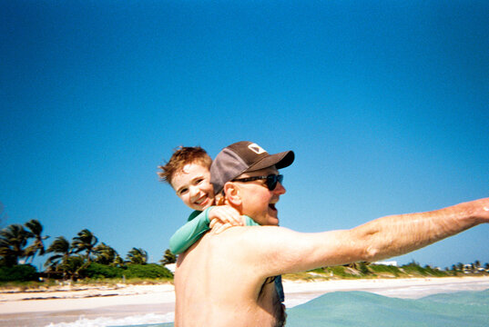 Candid happy film portrait of dad and child playing together at beach