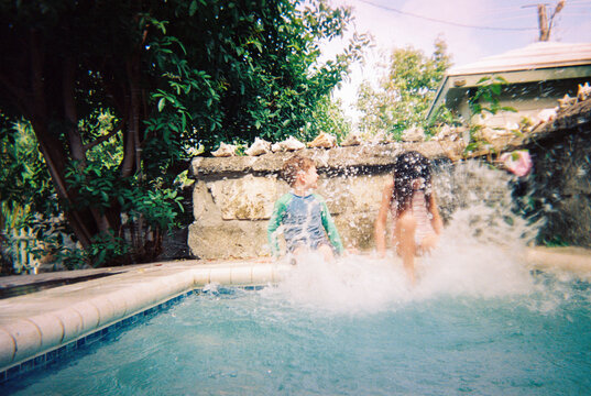 Candid action moment of kids on vacation splashing pool water