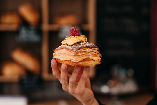 Delicious Dessert is Held by a Hand in a Bakery