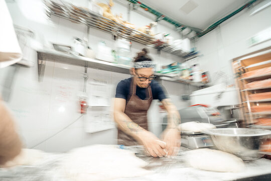 Baker kneading dough quickly in commercial kitchen