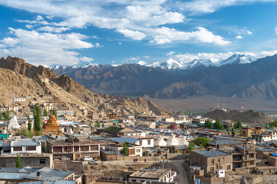 Ladakh town with Himalayan mountains and stupas under blue sky