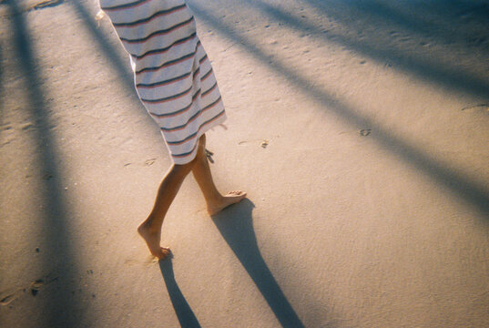 Detail of child walking on beach wrapped up in towel