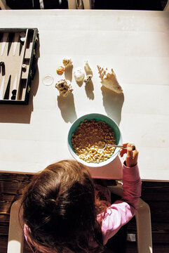 Child eating cereal at the breakfast table with seashells