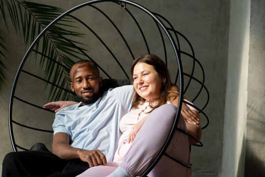 Interracial couple in a hammock swing enjoying the sunshine together