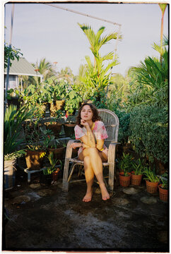 Woman sits on a terrace surrounded by lushly green tropical plants 