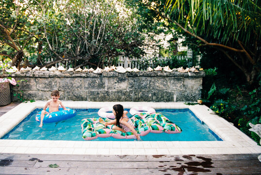 Kids play in backyard pool together while on family vacation
