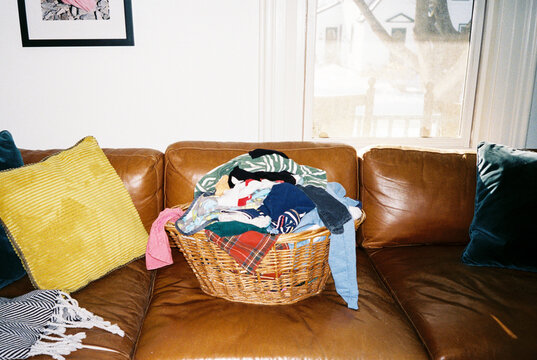 Basket of clean laundry in basket on couch at home