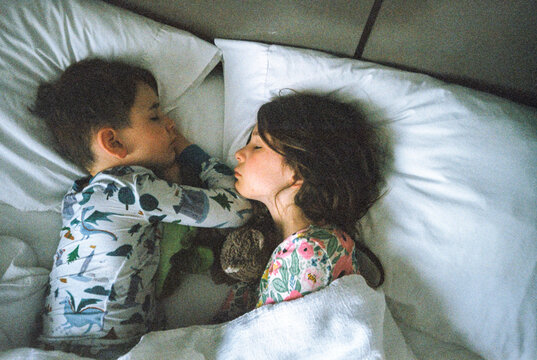 Siblings sleep in bed together