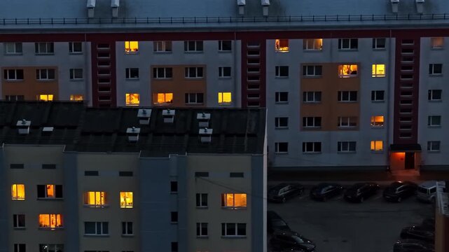 Evening aerial view of apartment building windows turning on and off in a residential district