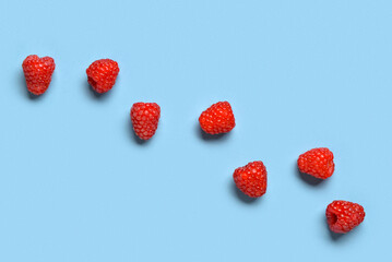 Many fresh raspberries on blue background