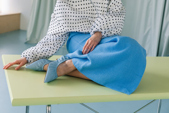 Minimal fashion detail with polka dot blouse and blue skirt