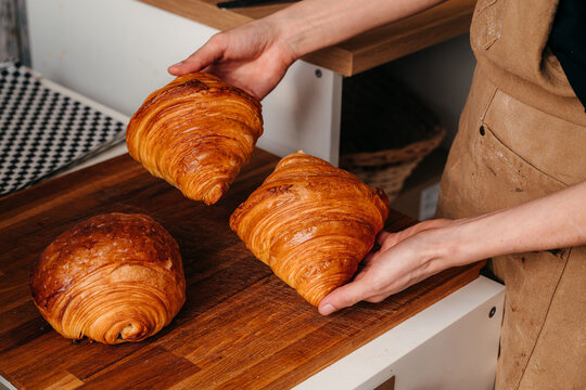 Freshly Baked Croissants Are Held in Hands in a Kitchen