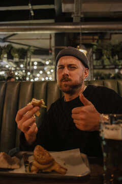 Customer enjoying burger at restaurant giving thumbs up