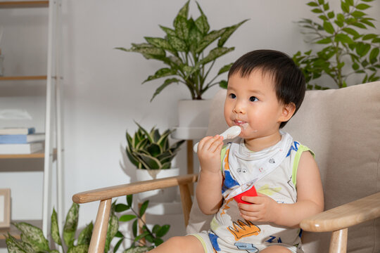 Adorable toddler enjoying a spoonful of yogurt at home